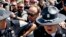 FILE - Alex Jones (C), an American conspiracy theorist and radio show host, is escorted out of a crowd of protesters after he said he was attacked in Public Square on July 19, 2016, in Cleveland, Ohio.
