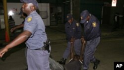 Police officers carry a man as they conduct a raid on the Central Methodist Church in downtown Johannesburg (AP Photo/Denis Farrell)