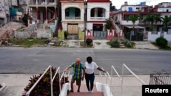 Jorge Enrique recibe ayuda de la cuidadora Silvia García para caminar de regreso a casa después de hacer ejercicio en un parque cercano en La Habana, Cuba, 8 de marzo de 2024. REUTERS/Alexandre Meneghini