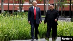 Presiden AS Donald Trump (kiri) dan pemimpin Korea Utara Kim Jong Un dalam pertemuan di Singapura, 12 Juni lalu (foto: dok). 