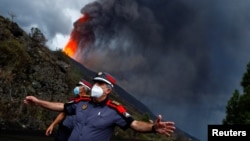 Police officers block a road as lava rises following the eruption of a volcano on the Island of La Palma, in Tacande, Spain, September 22, 2021.