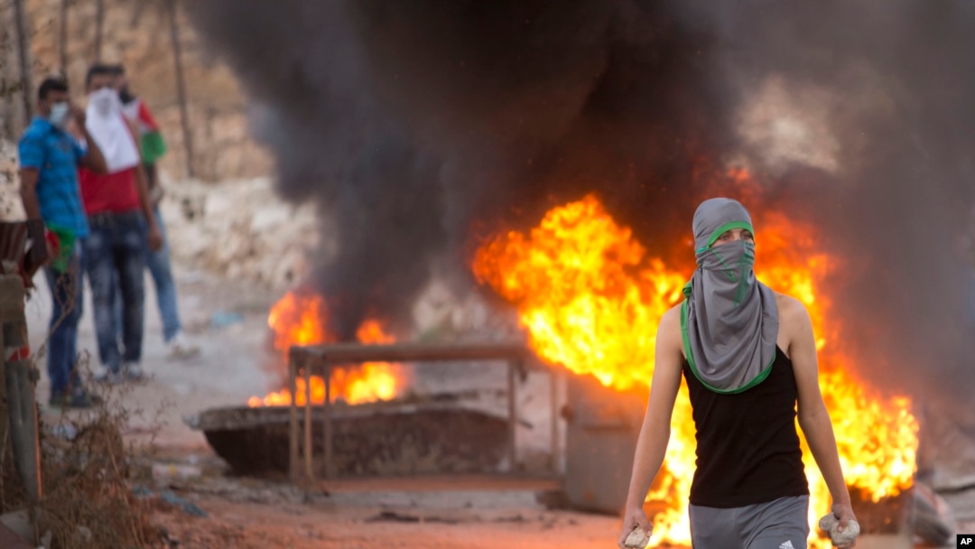 Seorang demonstran Palestina memegang batu dalam bentrokan dengan pasukan keamanan Israel, di pos pemeriksaan Hizme dekat Tepi Barat kota Ramallah, 30 September 2015.