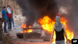 A Palestinian demonstrator holds rocks during clashes with Israeli security forces, at Hizme checkpoint near the West Bank city of Ramallah, Sept. 30, 2015.