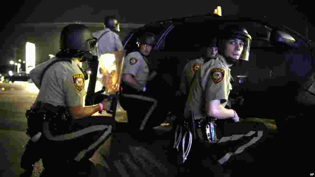 La police se protège derrière un véhicule lors d&#39;une manifestation à Ferguson, Missouri, 9 août 2015.