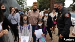 Nicole Tschabourian, 8, (L) and Leah Yousefi, 8, arrive with printed barcodes for the first day of school and return to full-time in-person learning after the COVID-19 break in Glendale, Los Angeles, California, Aug. 18, 2021.