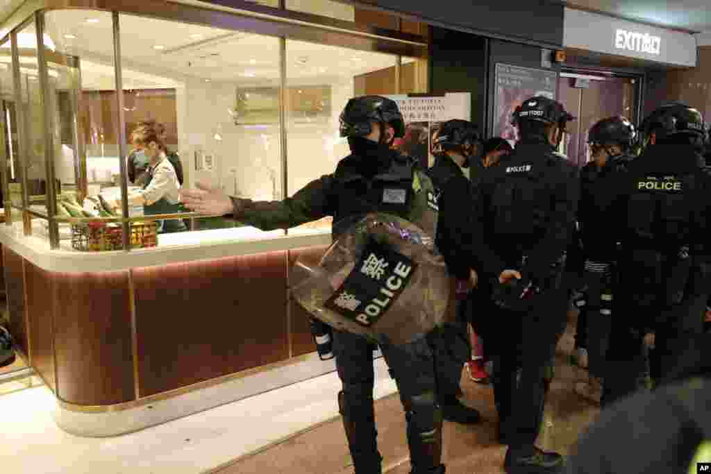 Un policía, al frente, hace gestos mientras comprueban la identidad de las personas en un centro comercial en la víspera de Año Nuevo en Hong Kong. 