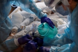 FILE - Critical care workers insert an endotracheal tube into a COVID-19 patient in the intensive care unit at Sarasota Memorial Hospital in Sarasota, Florida, Feb. 11, 2021.