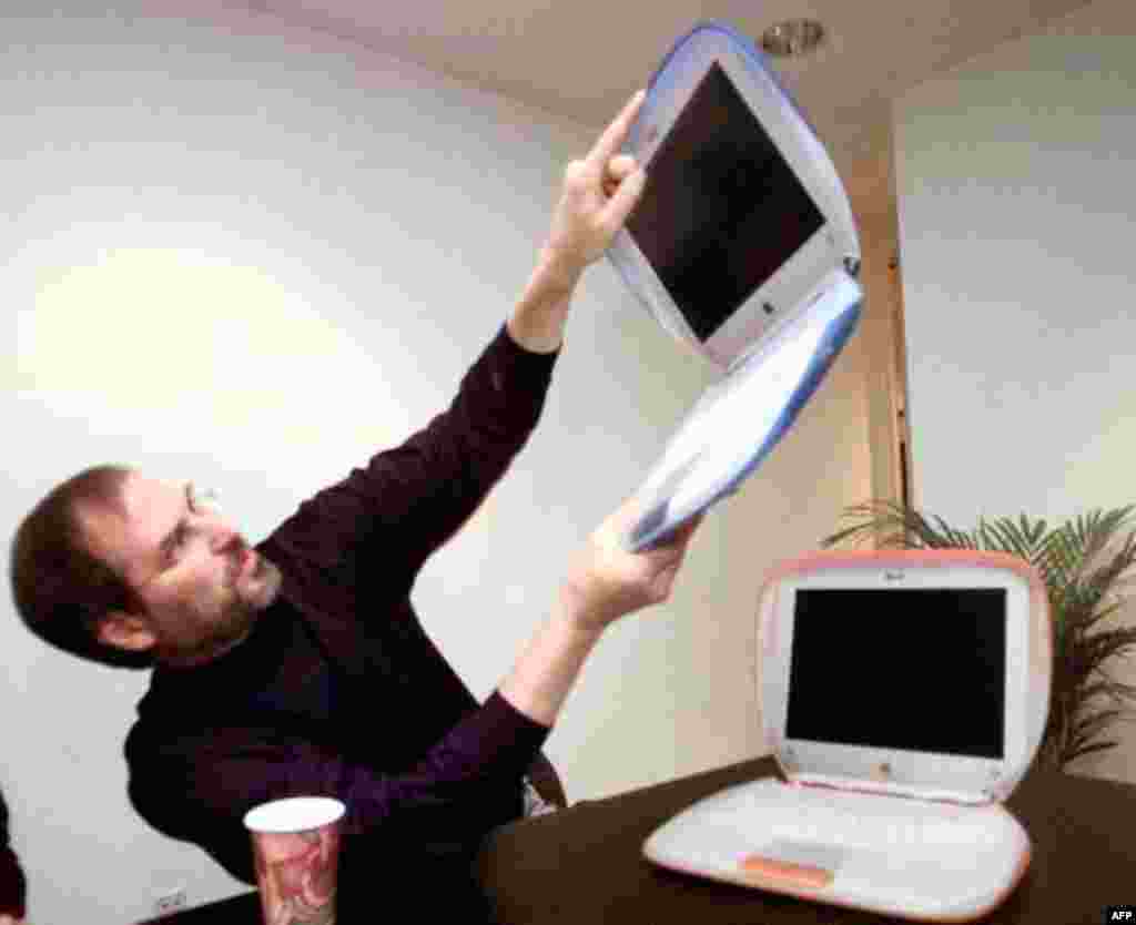 Steve Jobs, Founder and acting CEO of Apple Computer Inc., holds up one of the company's new consumer laptops called "iBook" after his keynote address at the Macworld Expo in New York, Wednesday July 21, 1999. The new computers, priced at $1,599, come in