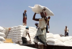 FILE - Men deliver U.N. World Food Program (WFP) aid in Aslam, Hajjah, Yemen, Sept. 21, 2018.