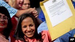 Newly-elected opposition congresswoman Marialbert Barrios holds up her credentials after receiving them from the National Electoral Council (CNE) in Caracas, Venezuela, Dec. 9, 2015.