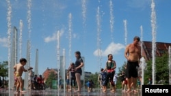 Kids and adults cool off in a fountain on the Rose Kennedy Greenway on the first day of a forecasted summer heatwave in Boston, Massachusetts, U.S., July 19, 2019. REUTERS/Brian Snyder