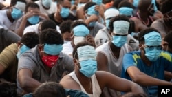 People from China, Vietnam and Ethiopia, believed to have been trafficked and forced to work in scam centers, sit with their faces masked while in detention after being released from the centers in Myawaddy district in eastern Myanmar, Feb. 26, 2025. 