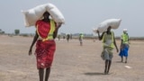 FILE - A women walk back to their homes after receiving food aid at a site in the Leer County region of South Sudan, April 11, 2017. 