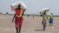 FILE - A women walk back to their homes after receiving food aid at a site in the Leer County region of South Sudan, April 11, 2017. 