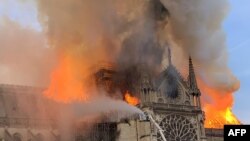 Api dan asap membubung dari atas Katedral Notre Dame di Paris, 15 April 2019.