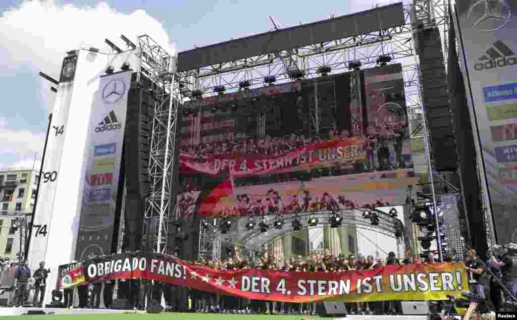 Pemain sepakbola Jerman melambaikan tangan ke para pendukung dari sebuah panggung ketika merayakan kemenangan merka di Piala Dunia Brazil 2014, di tempat nobar Fan Mile di Berlin, 15 Juli 2014.