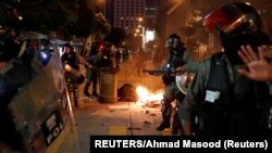 Polisi Hong Kong melintas di depan barikade yang dibakar untuk membubarkan demo anti-pemerintah, Sabtu, 2 November 2019. 