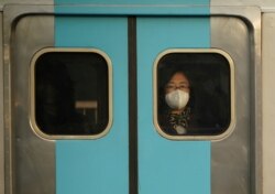 A woman wearing a mask to prevent contracting the coronavirus rides on a subway in Seoul, South Korea, Feb. 20, 2020.