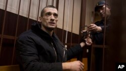 FILE - Russian artist Petr Pavlensky speaks to journalists as he sits in a cage in courtroom in Moscow, March 31, 2016. The artist, known for his political art performances, is one of three winners of the Human Rights Foundation's 2016 Vaclav Havel Prize for Creative Dissent.