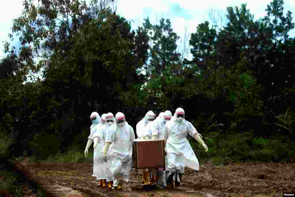 Municipal workers wearing protective gear bury a victim of the coronavirus disease (COVID-19) at a cemetery in Tarakan, North Kalimantan Province, Indonesia. (Antara Foto)