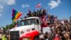 Duduk di atas kap truk, artis penyanyi, Ricky Martin, bergabung dengan selebriti dan demonstran Puerto Rico lainnya dalam protes untuk menuntut pengunduran diri Gubernur Ricardo Rossello, di San Juan, Puerto Rico, 22 Juli 2019. (Foto: dok).