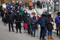 FILE - People wait in line for the COVID-19 vaccine in Paterson, N.J., Jan. 21, 2021.