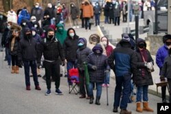 FILE - People wait in line for the COVID-19 vaccine in Paterson, N.J., Jan. 21, 2021.