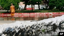 FILE - A monk examines sand bags built around his temple in Bangkok, Thailand, on Nov. 11, 2011. The 2011 floods challenged then-Prime Minister Yingluck Shinawatra's government, just as 2024 flooding threatens to challenge new Prime Minister Paetongtarn Shinawatra.