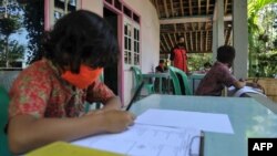 Henrikus Suroto (tengah), seorang guru SD, membuka kelas di rumah murid-muridnya di Magelang, Jawa Tengah, setelah sekolah terpaksa ditutup karena pandemi Covid-19, 20 Mei 2020. (Foto: AFP)