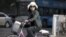 A Chinese woman wearing a face mask on a bicycle waits to cross a street in Beijing May 31, 2013. 