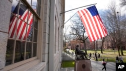 People walk past the John Harvard statue in Harvard Yard, Dec. 17, 2024, on the campus of Harvard University in Cambridge, Mass.