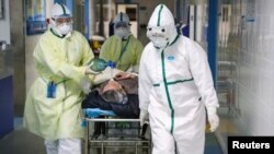 중국 후베이성 우한의 병원에서 보호장비를 착용한 의료 관계자들이 코로나바이러스에 감염된 환자를 격리병동으로 옮기고 있다.