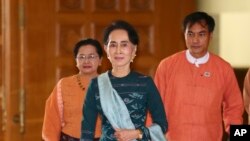 FILE - Myanmar's de facto leader Aung San Suu Kyi, center, arrives at the country's parliament in Naypyitaw, March 15, 2016. 