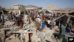 People gather on the rubble of shops destroyed by a Saudi-led airstrike at a market in Sana'a, Yemen, July 20, 2015. 