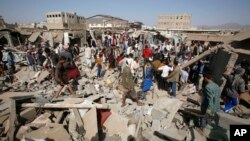 FILE - People gather on the rubble of shops destroyed by a Saudi-led airstrike at a market in Sana'a, Yemen, July 20, 2015. 