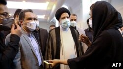 A handout picture provided by the Iranian presidency on Aug. 10, 2021, shows Iran's President Ebrahim Raisi (C) during a visit to Imam Khomeini Hospital and Corona Vaccination Center in Tehran.