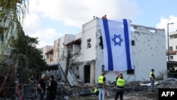 Radnik hitne pomoći fotografiše izraelsku zastavu postavljenu na zid oštećene zgrade u Kiryat Bialik u okrugu Haifa u Izraelu, nakon izvještaja o napadu libanonskog Hezbollaha 22. septembra 2024.