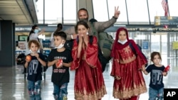 Families evacuated from Kabul, Afghanistan, walk through the terminal before boarding a bus after they arrived at Washington Dulles International Airport, in Chantilly, Va., on Friday, Aug. 27, 2021. (AP Photo/Jose Luis Magana)