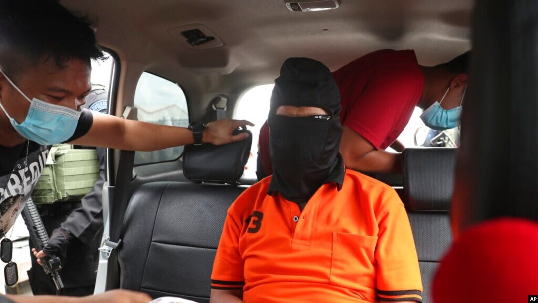 Police officers escort suspected militant Zulkarnaen, center, who is also known as Aris Sumarsono, upon arrival at Soekarno-Hatta International Airport in Tangerang, Indonesia, Dec. 16, 2020.