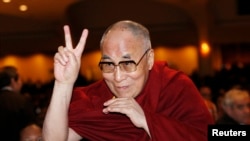 FILE - The Dalai Lama directs a peace sign toward the head table, where U.S. President Barack Obama was seated, during the National Prayer Breakfast in Washington, Feb. 5, 2015.