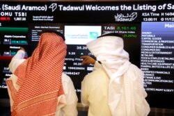 FILE - Stock market officials watch the market screen displaying Saudi Arabia's state-owned oil company Aramco after the debut of Aramco's initial public offering on the Tadawul exchange in Riyadh, Saudi Arabia, Dec. 11, 2019.
