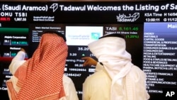 FILE - Stock market officials watch the market screen displaying Saudi Arabia's state-owned oil company Aramco after the debut of Aramco's initial public offering on the Tadawul exchange in Riyadh, Saudi Arabia, Dec. 11, 2019. 