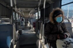 A woman wearing a face mask sits inside a public bus, as the country is hit by an outbreak of the novel coronavirus, in Beijing, China, Feb. 15, 2020.