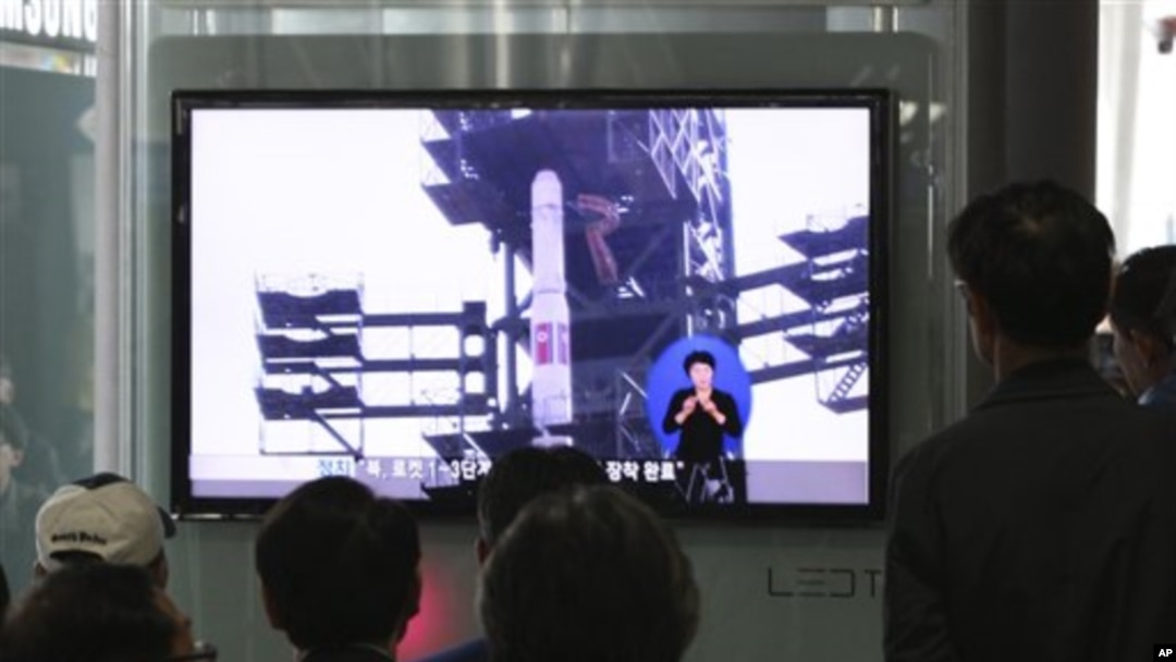 Warga Korea Selatan menyaksikan program televisi di sebuah stasiun kereta api di Seoul, yang menampilkan liputan terkait rencana peluncuran roket Unha-3 Korea Utara, Minggu (8/4).