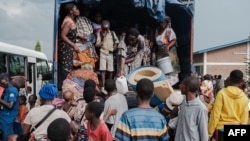 Congolese refugees displaced by ongoing clashes in eastern Democratic Republic of Congo carry their belongings as they disembark from a truck upon arrival at the Gihanga refugee transit camp in Gihanga on Feb. 17, 2025.