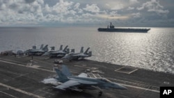 En esta foto proporcionada por la Armada de EE.UU., un Super Hornet F/A-18E aterriza en la cubierta del USS Ronald Reagan (CVN 76), mientras el USS Nimitz (CVN 68) navega junto al Mar del Sur de China, el lunes 6 de julio de 2020.