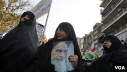 Wanita Iran mengikuti unjuk rasa di depan bekas gedung Kedutaan AS di Teheran dengan membawa poster Ayatollah Khomeini, 4 November 2010.