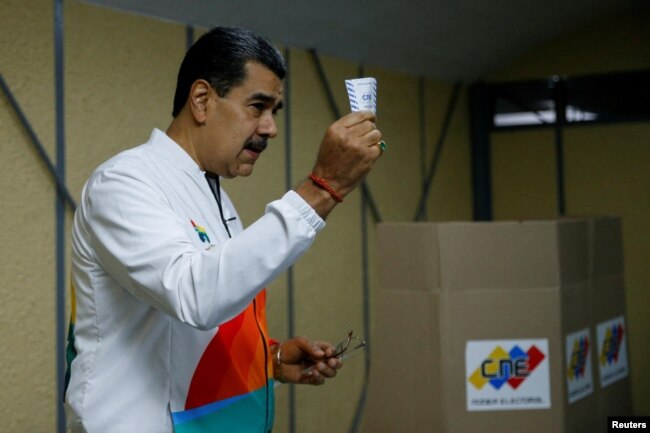 Venezuela's President Nicolas Maduro shows his ballot during an electoral referendum over Venezuela's rights to the potentially oil-rich region of Esequiba in Caracas, Venezuela on December 3, 2023. (REUTERS/Leonardo Fernandez Viloria)