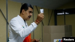 Venezuela's President Nicolas Maduro shows his ballot during an electoral referendum over Venezuela's rights to the potentially oil-rich region of Esequiba, which has long been the subject of a border dispute between Venezuela and Guyana, in Caracas, Venezuela, Dec. 3, 2023