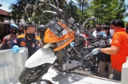 Indonesian police remove a motorcycle that was used by bombers during a reconstruction of the explosion in Makassar, March 29, 2021.